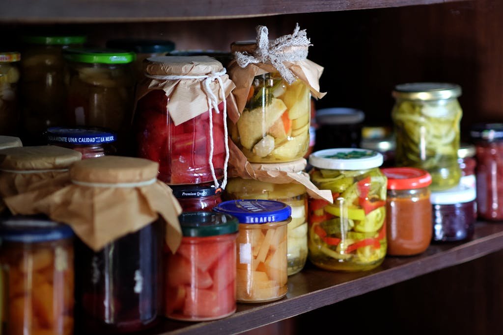 A variety of homemade preserves and pickles stored on a rustic wooden pantry shelf. how to pickle jerusalem artichoke