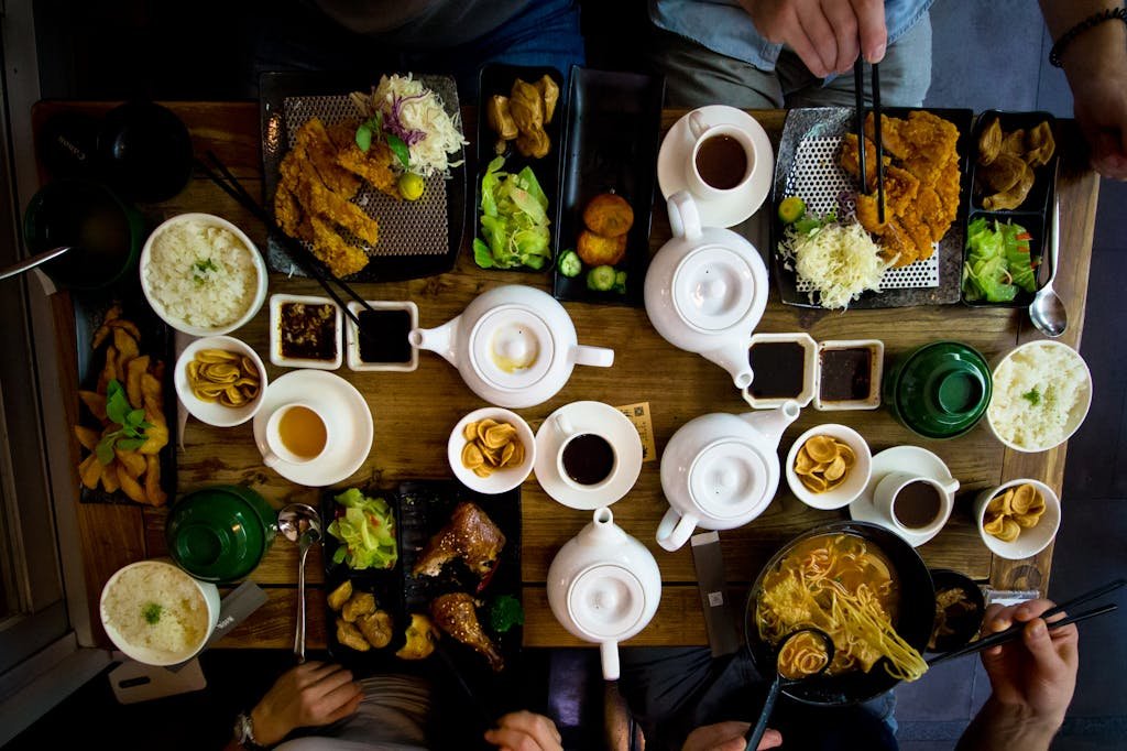 A vibrant spread of traditional Taiwanese dishes with teapots and sides on a wooden table.