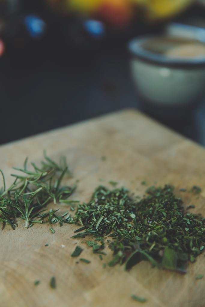 Chopped fresh rosemary herbs on a wooden board, ideal for cooking and culinary themes.
