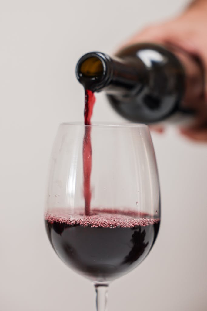 Close-up shot of red wine being poured into a glass. Perfect for wine-related themes.