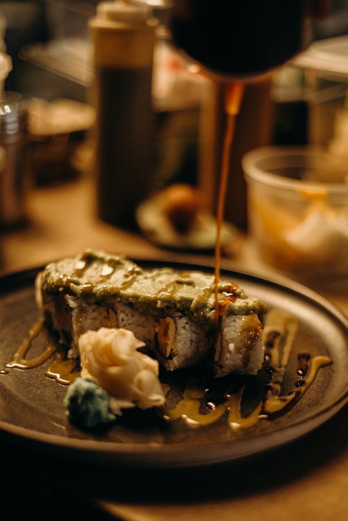 Mouth-watering close-up of gourmet sushi with sauce drizzle on a dark plate.