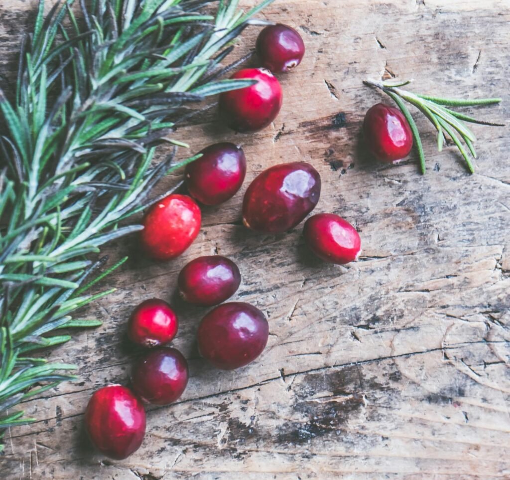 Top view of cranberries and rosemary on a rustic wooden surface, perfect for holiday themes.