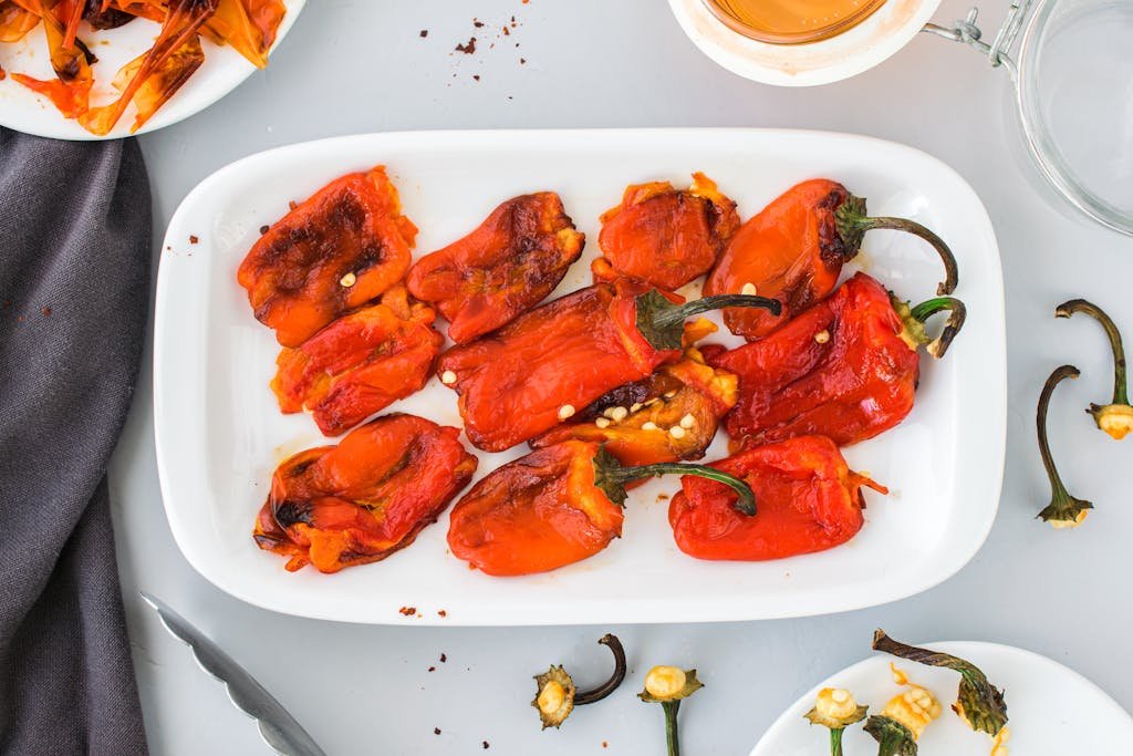 Top view of roasted red peppers on a white plate, perfect for snack or appetizer ideas.