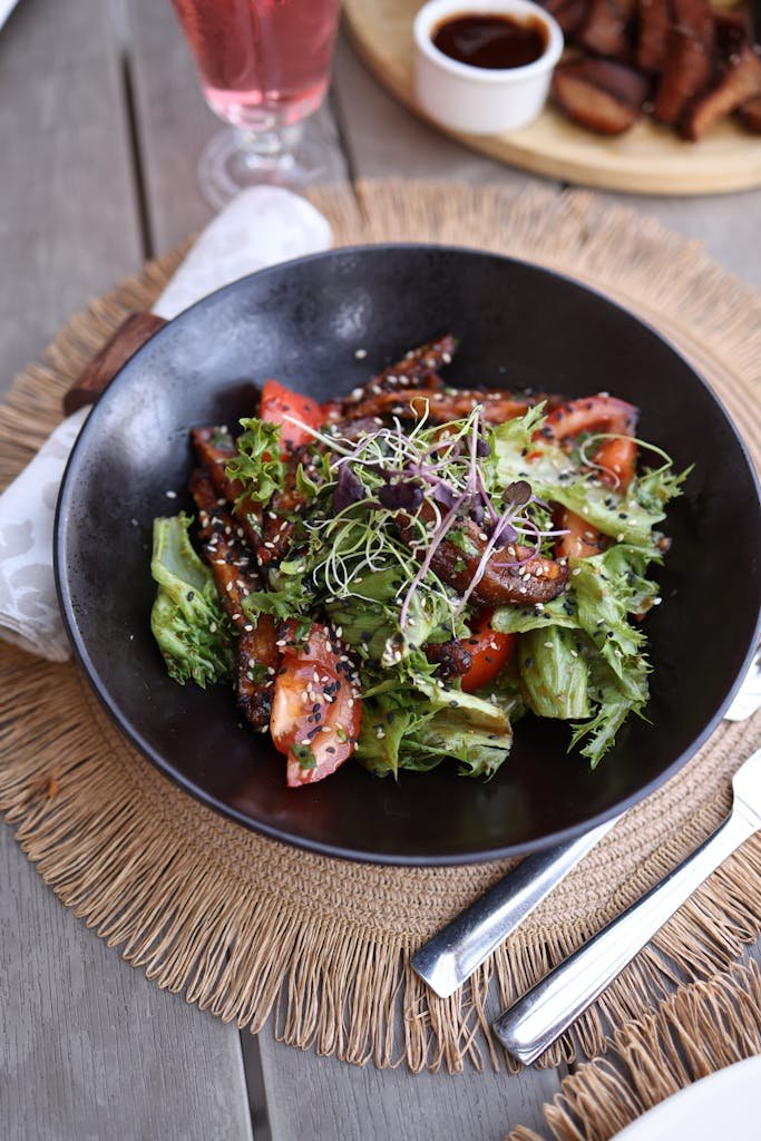 Delicious gourmet salad with fresh tomato and lettuce served elegantly on a wooden table. Black g