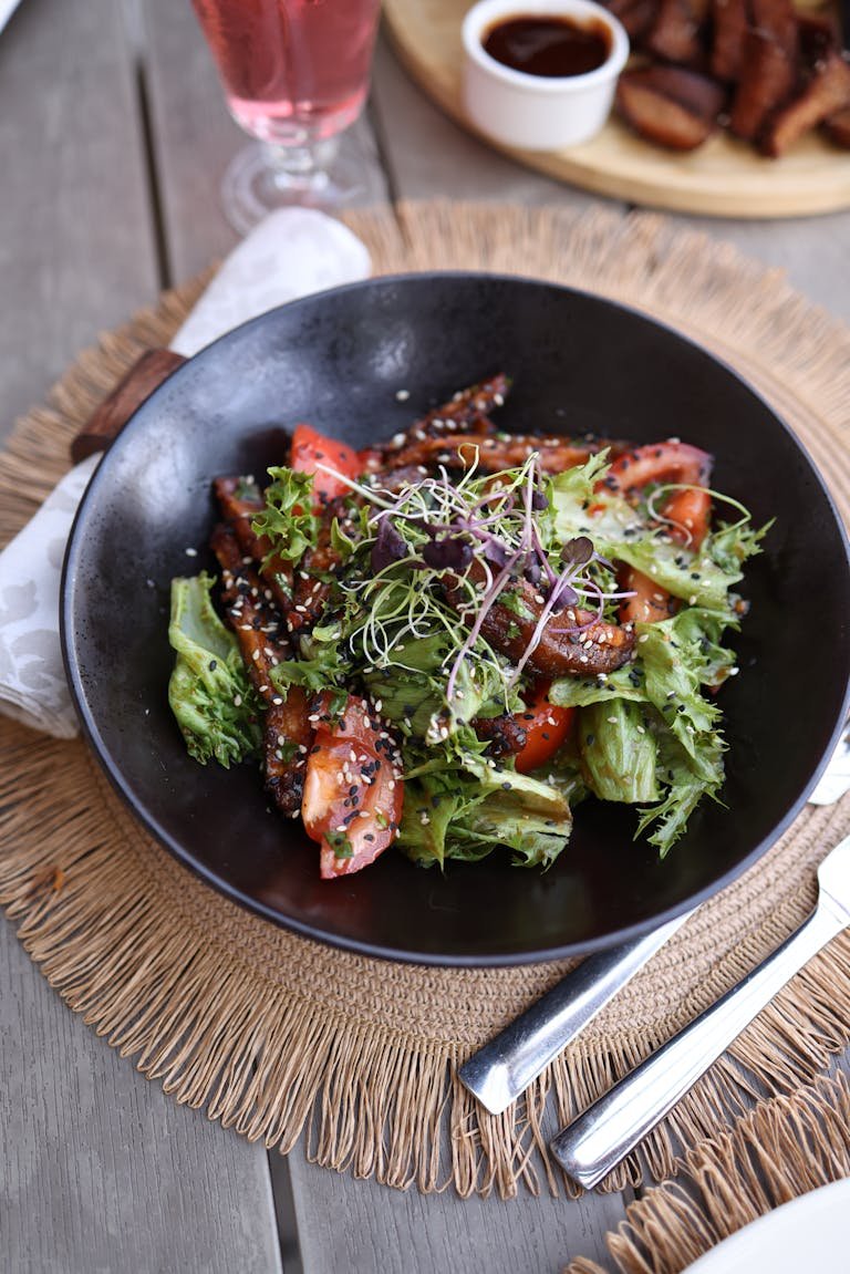Delicious gourmet salad with fresh tomato and lettuce served elegantly on a wooden table. Black g