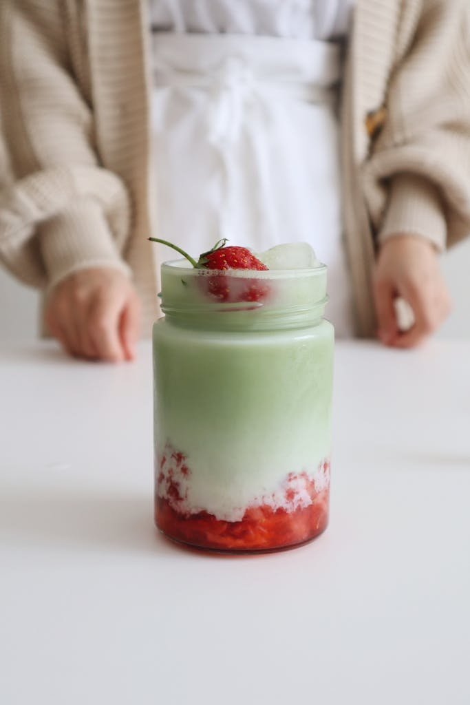 Delicious homemade strawberry matcha latte with ice served in a glass jar. Perfect for a refreshing break.