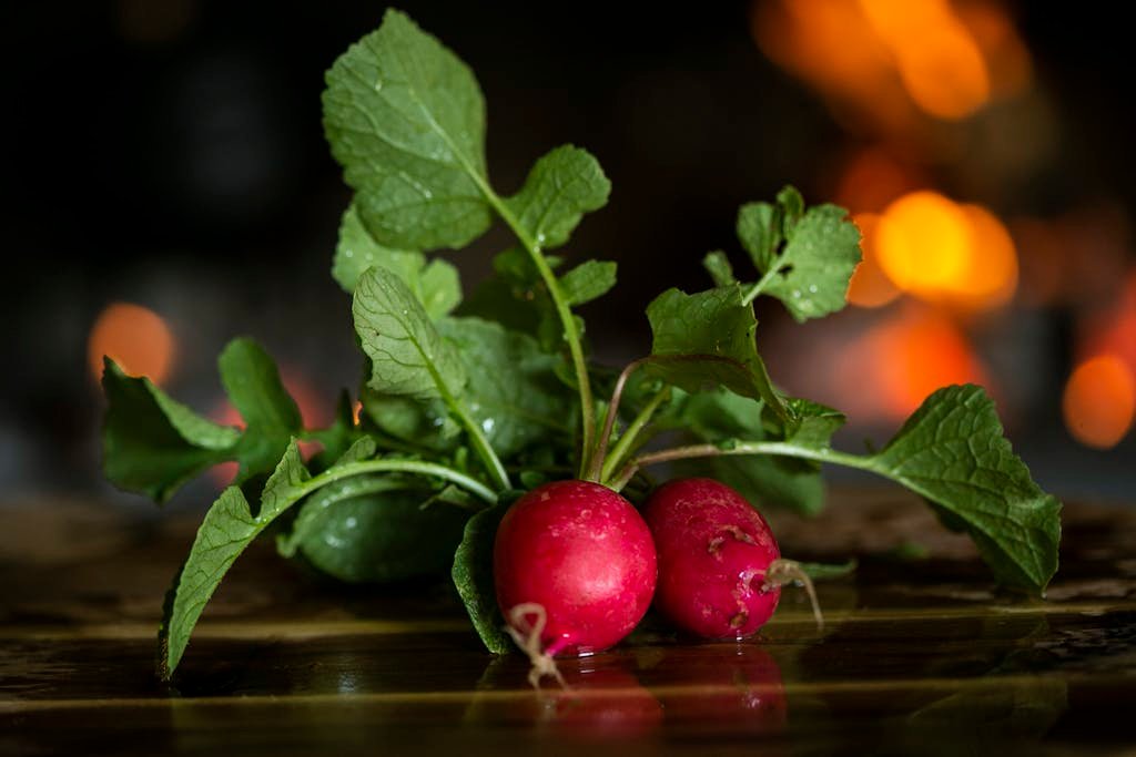 Close-up of fresh radishes with leaves on a wooden table, highlighting freshness.
