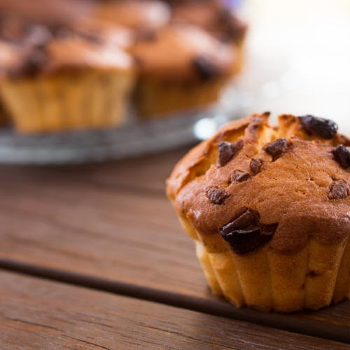 A close-up view of a chocolate chip muffin on a wooden table, perfect for food blogs.