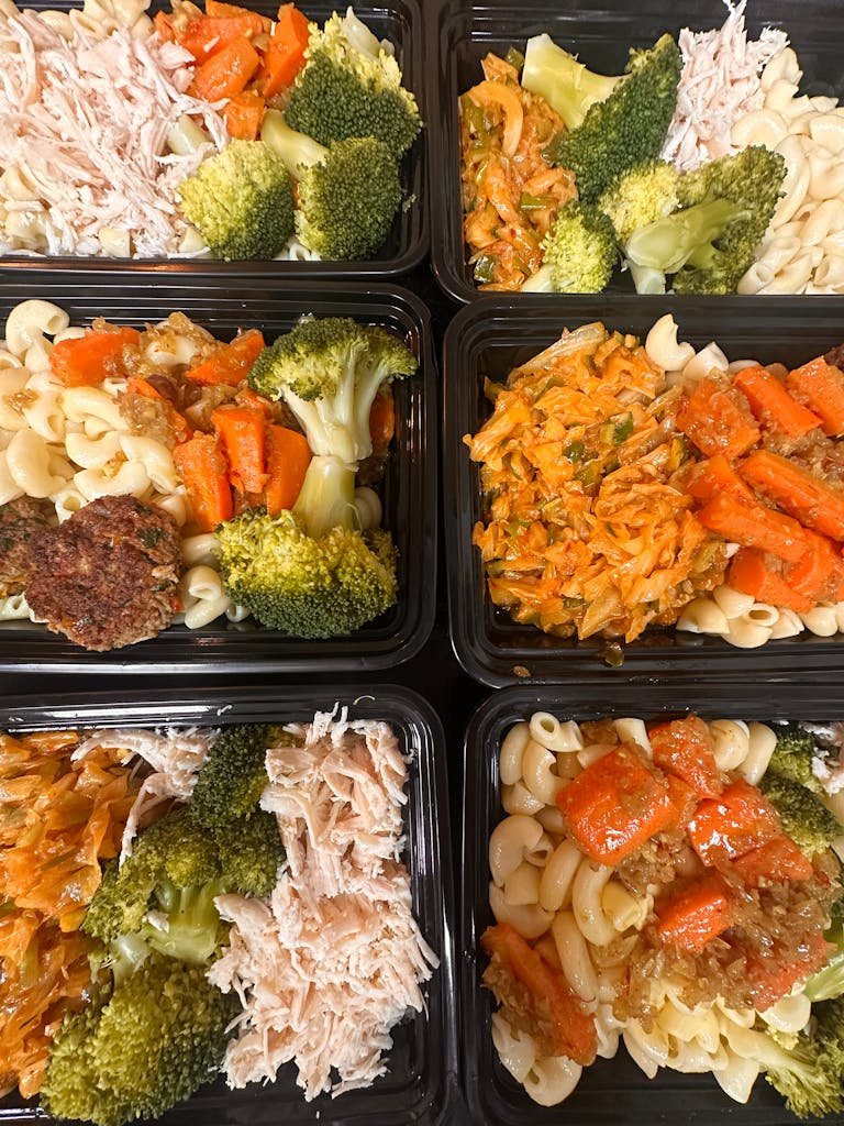 Easy pasta salad lunchbox - Colorful meal prep trays with pasta, broccoli, shredded chicken, and carrots, ready for healthy eating.
