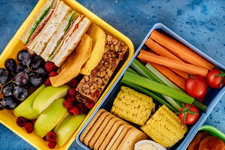 Top view of a nutritious packed lunchbox with sandwiches, vegetables, and fruits. school lunchbox meal prep